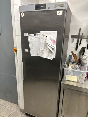 a stainless steel refrigerator in a kitchen with a lot of clutter on the door