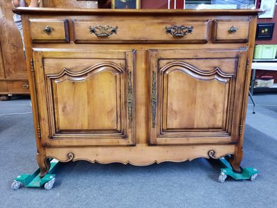 une armoire ancienne en bois, à deux portes et un tiroir, montée sur roulettes