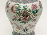 a white vase with flowers on it sitting on a table