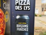a large pizza sitting next to a trash can on the side of the road