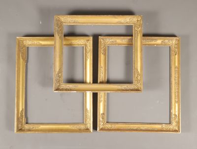 trois cadres dorés accrochés au mur, avec un miroir au milieu