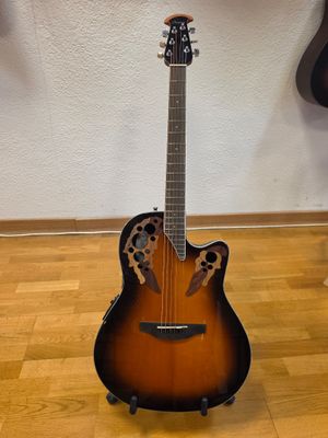 an acoustic guitar sitting on top of a hard wood floor next to a wall