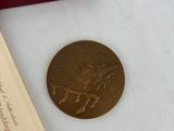 a gold medal sitting next to a book and a pair of earrings