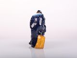 a figurine of a man with a suitcase on a white surface