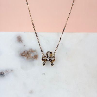 gold plated skull and crossbone necklace on a marble surface