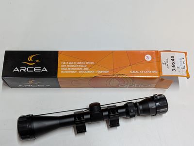 a close up of a rifle scope with a box on a table