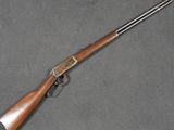 un fusil avec une crosse en bois posée sur une surface grise