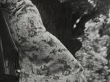 black and white photograph of a woman leaning against a fence