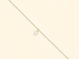 a close up of a gold chain with a small letter on it