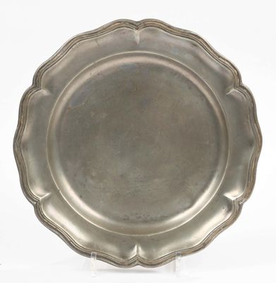 an antique silver plate with scalloped edges on a white background