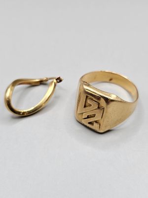 une image représentant une bague en or et une boucle d'oreille en or posées sur une surface blanche