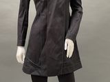 mannequin dressed in a black coat and leggings stands in front of a gray background