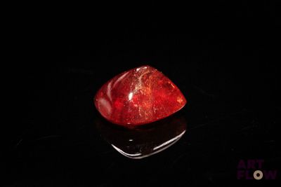 a close up of a red stone sitting on top of a black surface