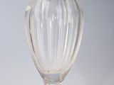 un vase en verre orné d'un couvercle doré, posé sur un socle blanc