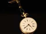 an old pocket watch with a tie bar on a black background