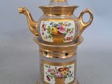 une théière dorée et blanche ornée de fleurs