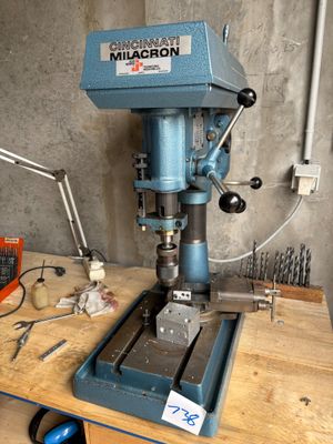 a drill press sitting on a workbench in a workshop