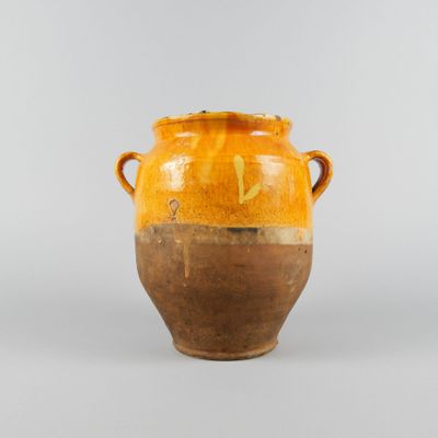 un vase orange et marron posé sur une table blanche