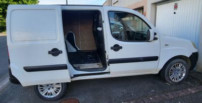 a small white van with its door open in a parking lot