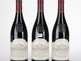 trois bouteilles de vin rouge posées sur une table blanche
