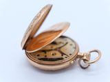 a gold pocket watch sitting on a white surface