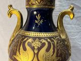 un vase bleu et or posé sur une surface blanche