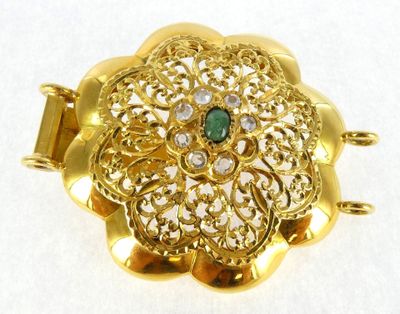 an image of a gold brooch with a green stone in the center