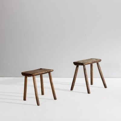 two small wooden stools sitting on top of a white floor