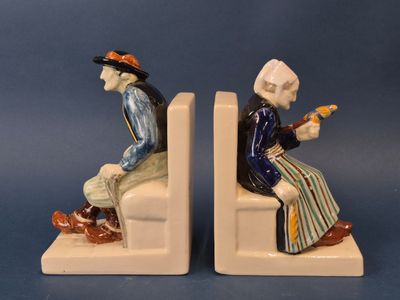 pair of ceramic figurines of two people sitting on a bench