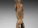 une statue en bois d'un homme avec un chapeau sur la tête