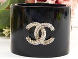 a close up of a black bracelet with a flower in the background