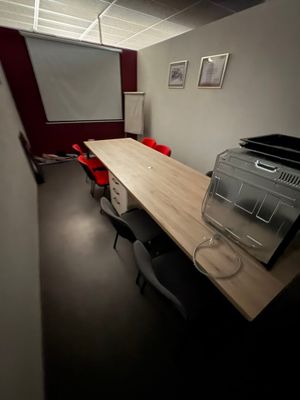 a room with a table, chairs, and a projector screen