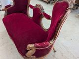 une chaise ancienne rouge et or dans une pièce où l'on aperçoit d'autres meubles à l'arrière-plan