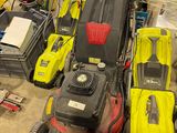 Plusieurs tondeuses à gazon sont alignées sur le sol d'un garage