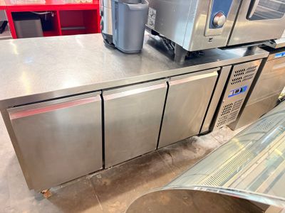 stainless steel counter top with two ovens and a trash can on it