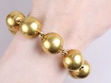 gold ball bracelet on a woman ' s hand