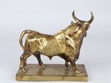 brass statue of a bull on a wooden base on a white background