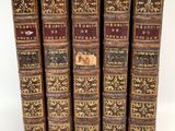 six vieux livres sont alignés sur une surface blanche