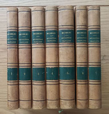 six old books are lined up on a wooden table