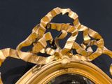 a mirror with a gold frame on a black wall