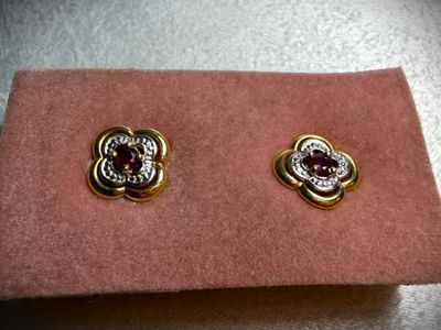 a close up of a pair of earrings on a pink cloth