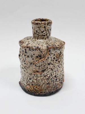 un petit vase posé sur une surface blanche