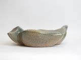 a green bowl with a bird on it on a white surface