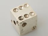 a silver dice with holes on it on a white surface