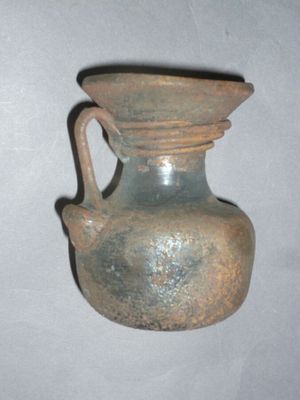 un petit vase marron muni d'une anse, posé sur une table