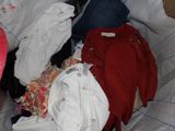 a pile of clothes that is sitting on a bed