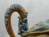 a close up of a blue and yellow vase with a bird on it