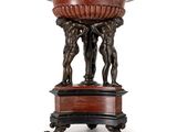 un grand socle en bronze et en marbre rouge surmonté de deux hommes tenant un bol