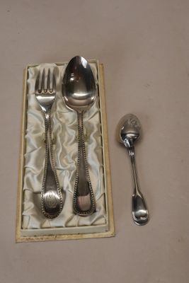 une cuillère et une fourchette en argent dans une boîte contenant une cuillère et un repose-cuillère