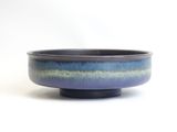 purple and blue ceramic bowl with black rim on white background